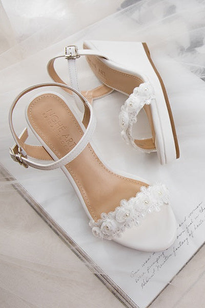 Top view of matte white leather canoe heels with white rose lace trim, highlighting the delicate floral design.