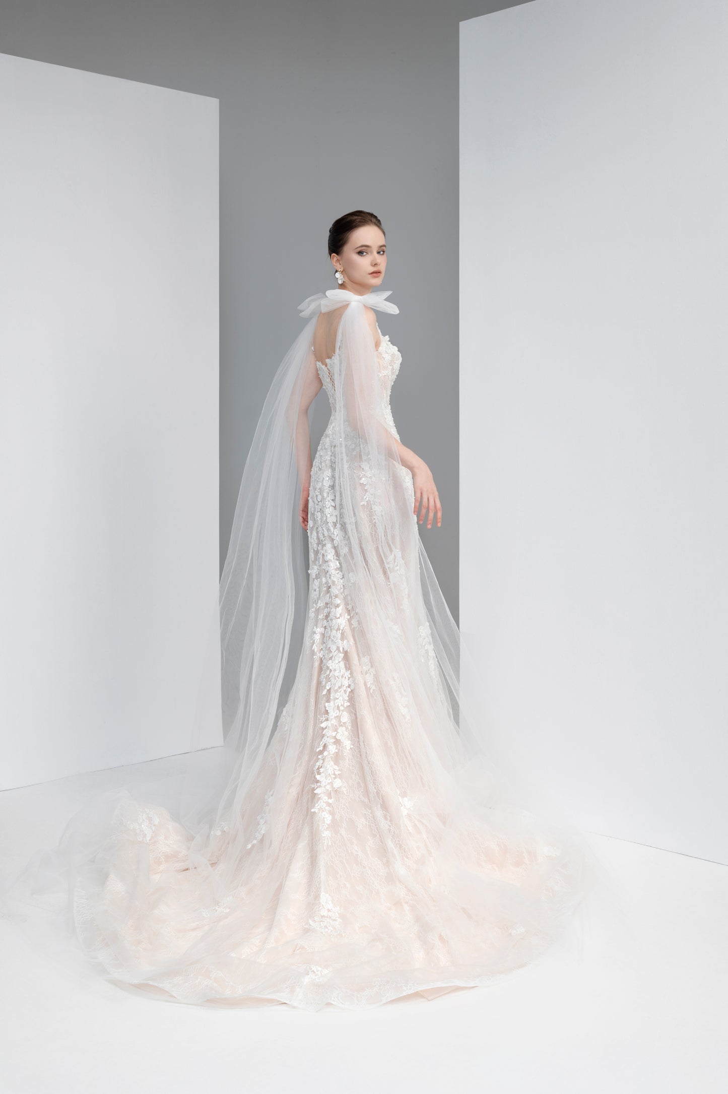 Woman wearing a white wedding dress with a long train in a minimalistic setting