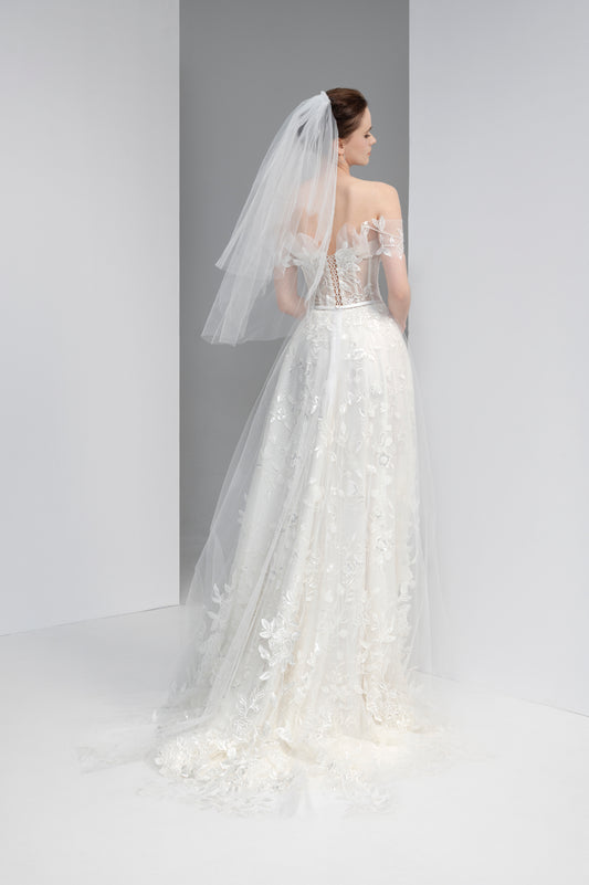 Bride in a white wedding dress with a long veil against a gray background