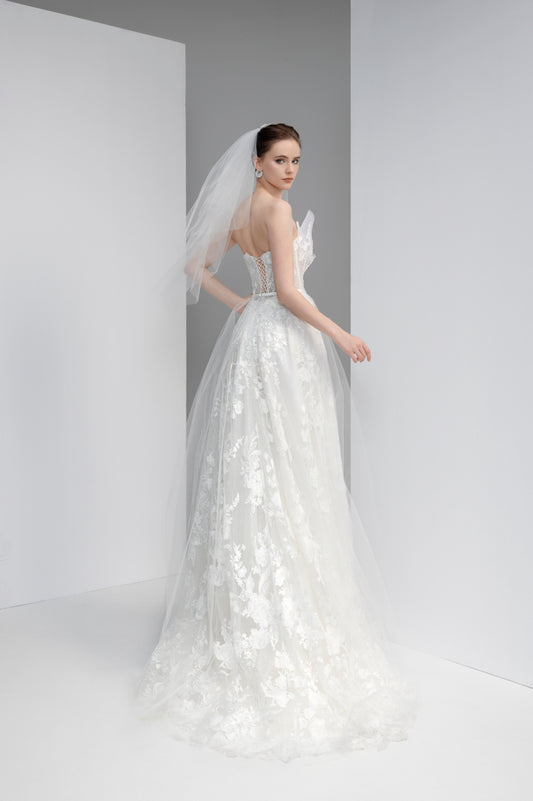 Woman wearing a white wedding dress with a veil against a plain background