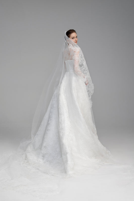 White wedding dress with a long veil on a gray background