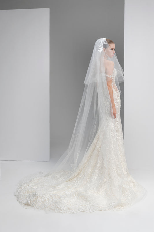 White wedding dress with a long veil on a plain background