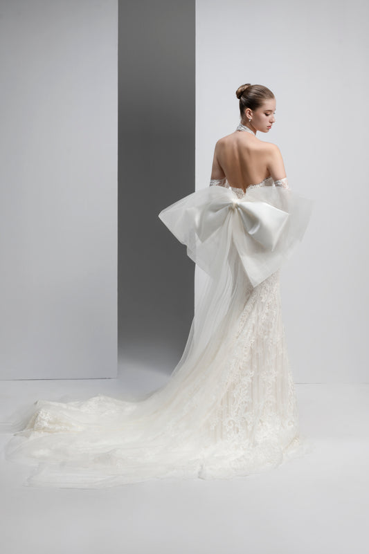White wedding dress with a large bow detail on a plain background