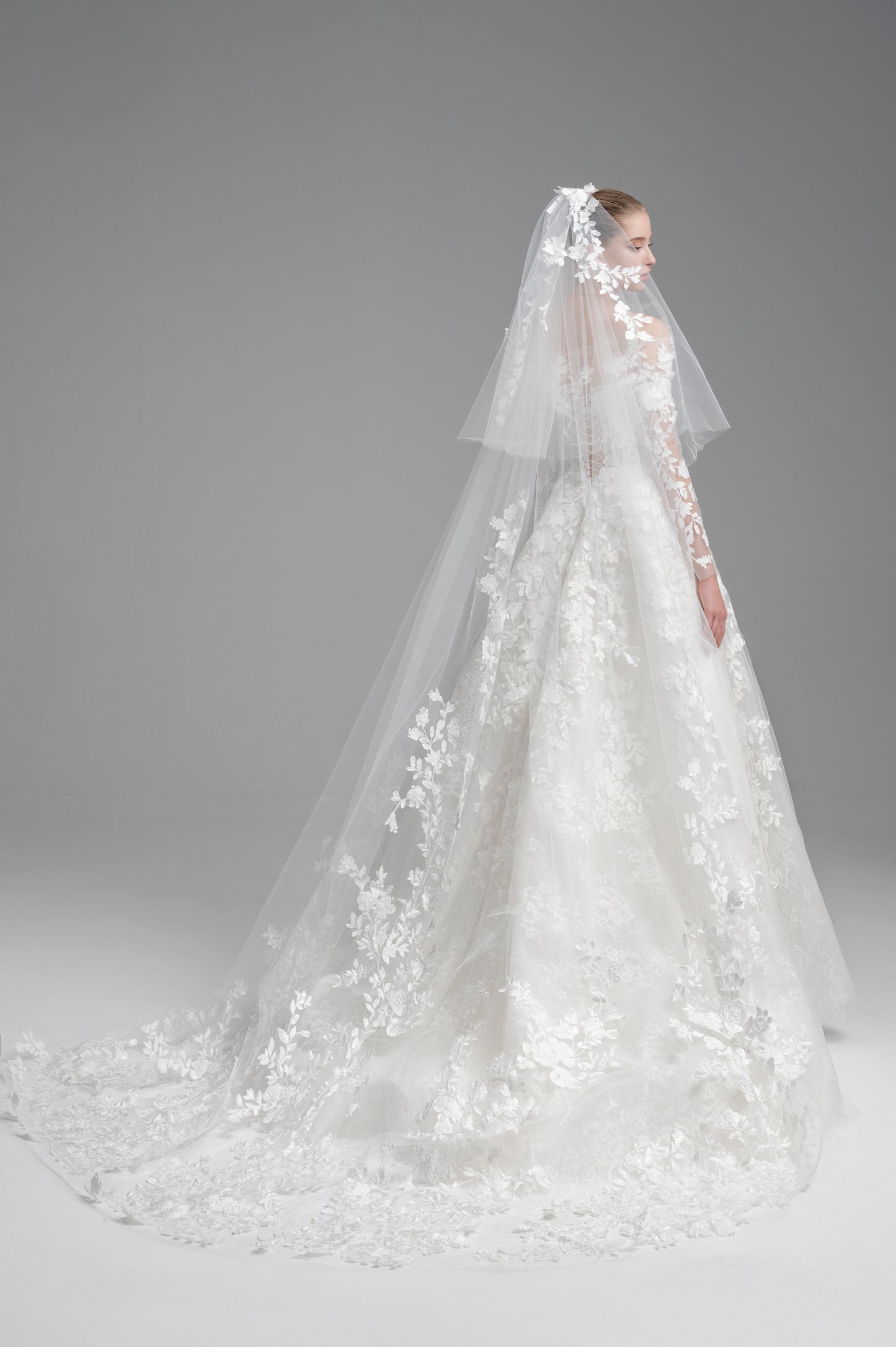 Elegant white wedding dress with a long veil on a gray background