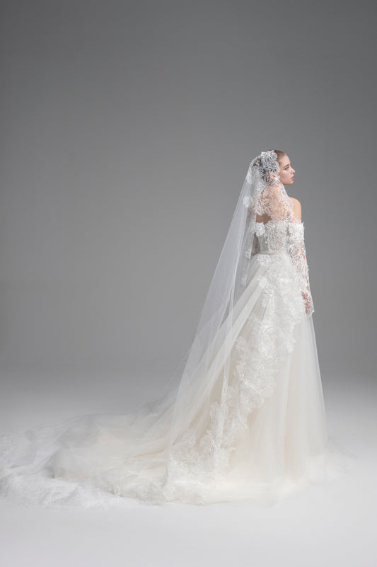 Bride in a white wedding dress with a long veil against a gray background