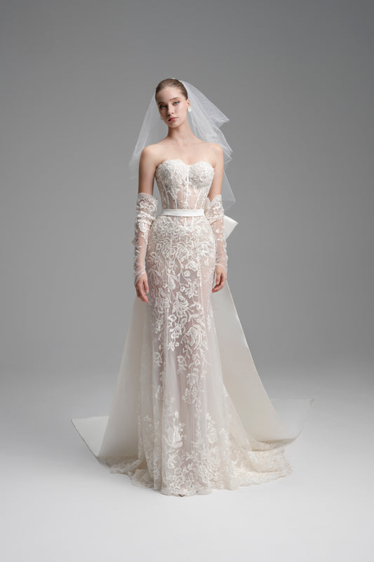 Model wearing a white lace wedding dress with a veil on a gray background