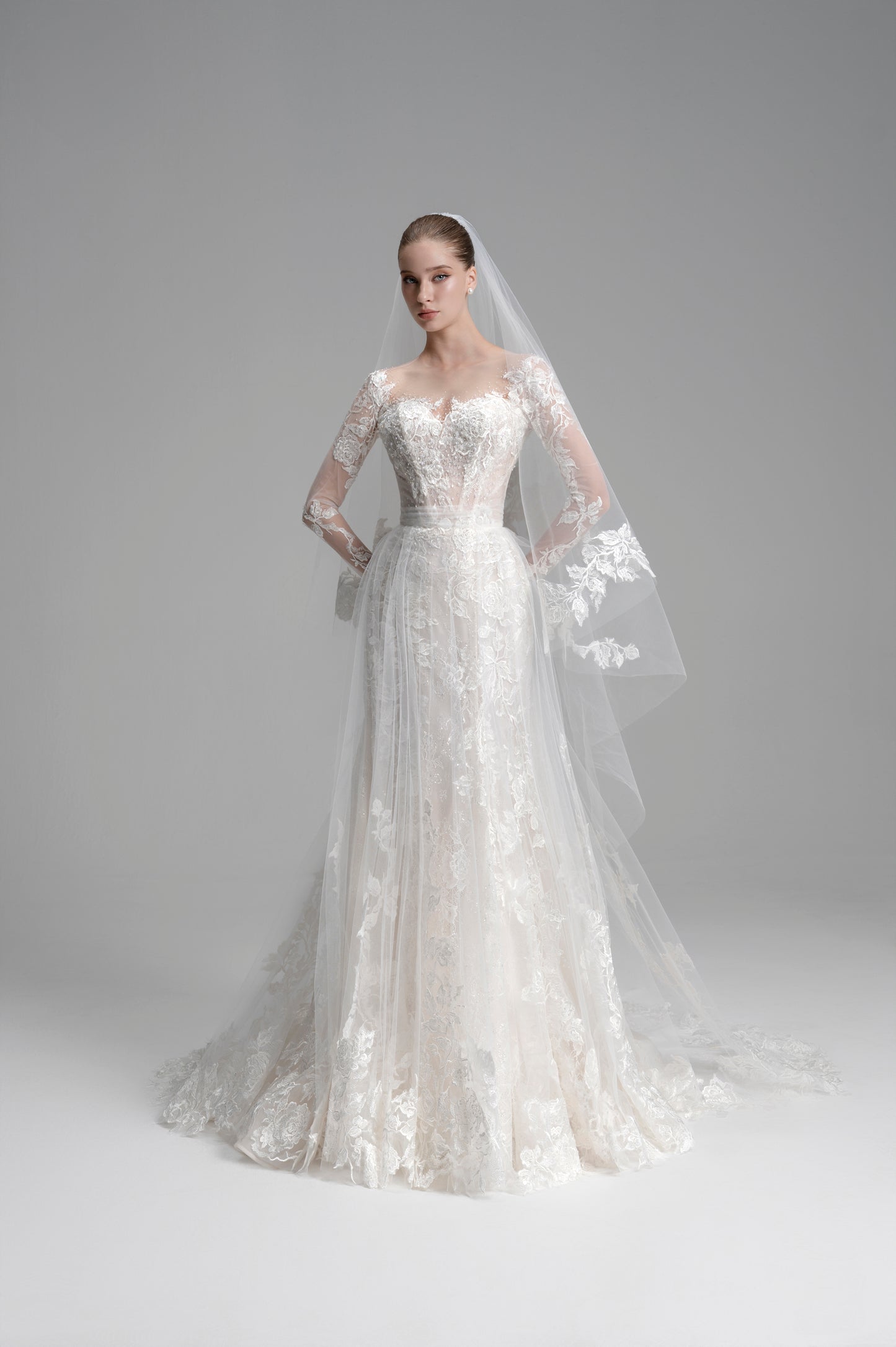 White wedding dress with long sleeves and a veil on a gray background