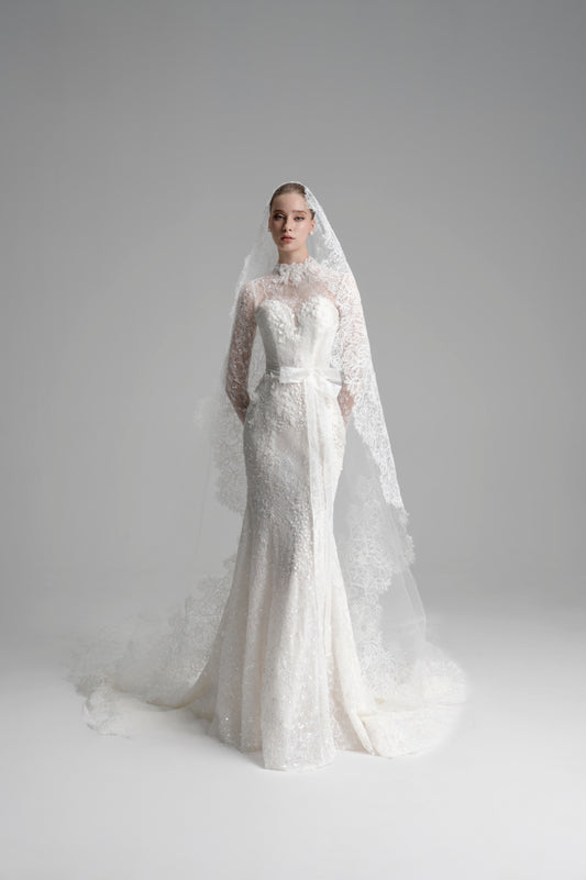 White lace wedding dress with a long train and veil on a gray background