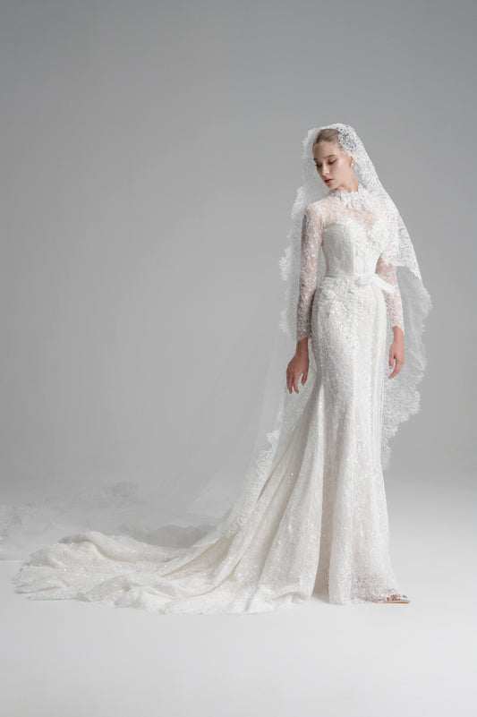 White lace wedding dress with a long train on a plain background