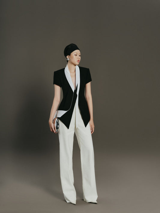 Model wearing a black and white outfit with a plain background