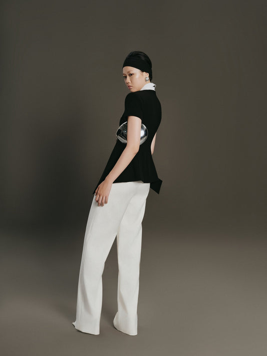 Person wearing a black t-shirt with a white graphic and white pants on a gray background