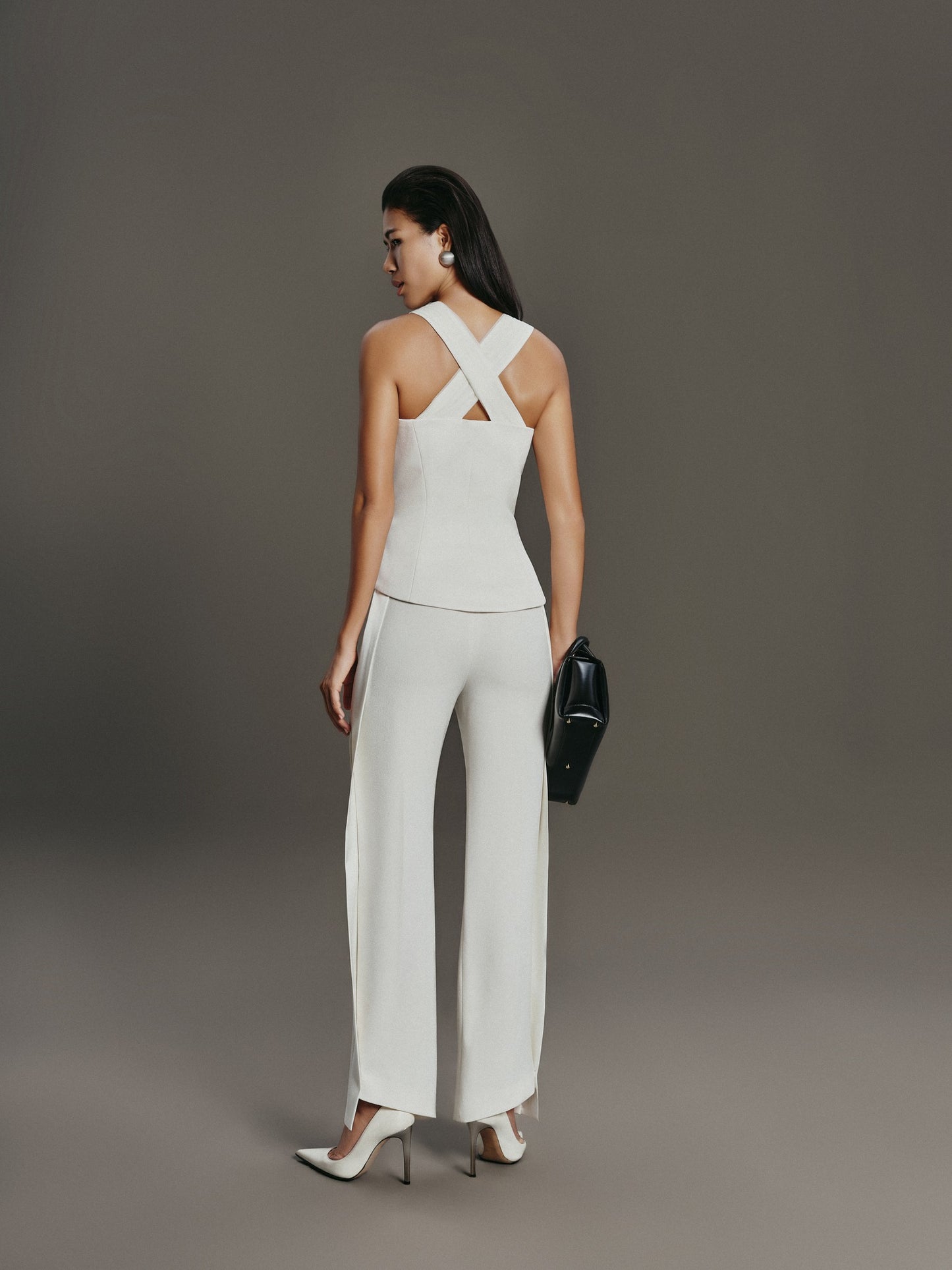 Woman wearing a white outfit with a criss-cross back design on a gray background
