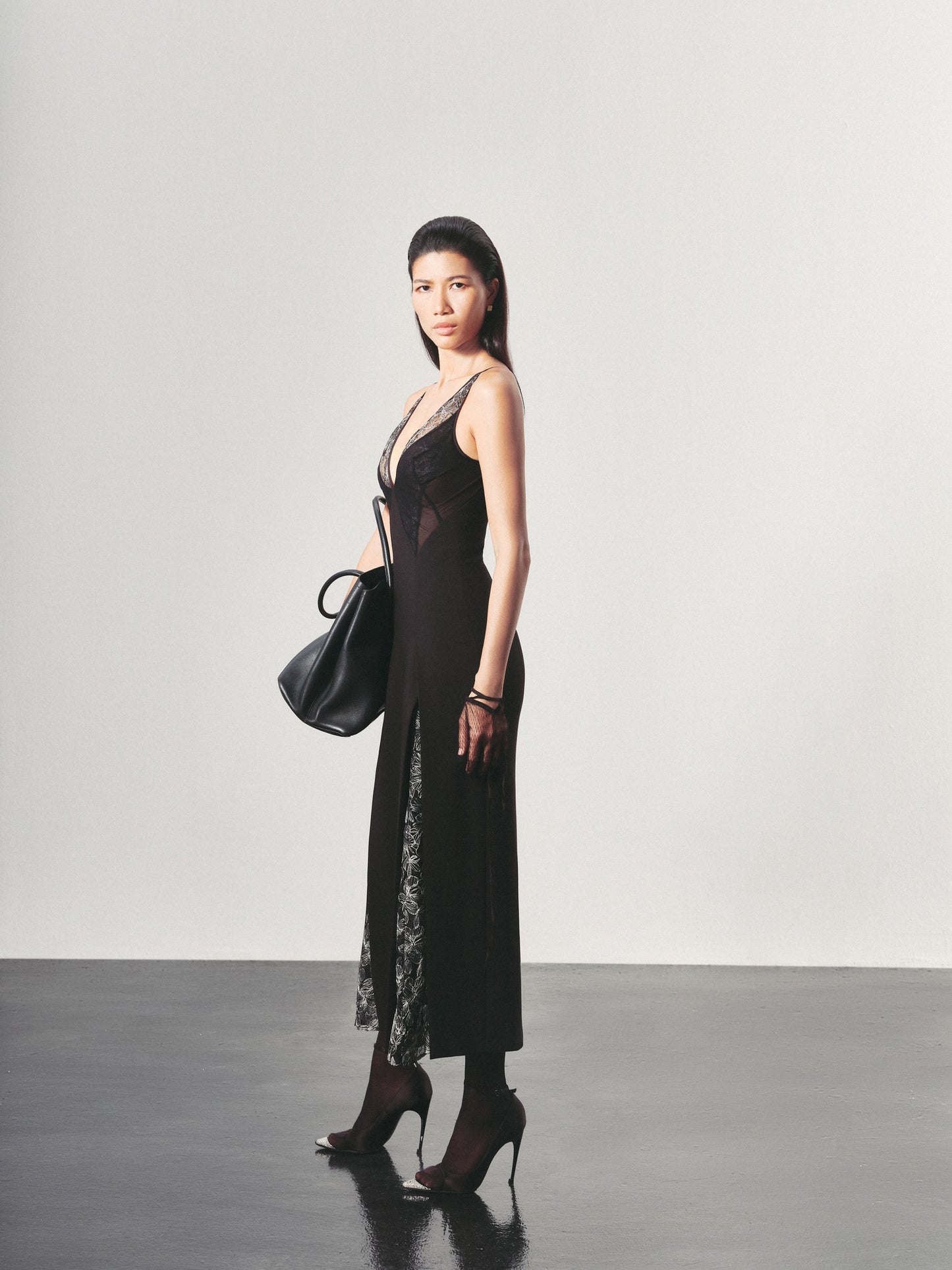 Woman wearing a black dress with sheer panels against a plain background