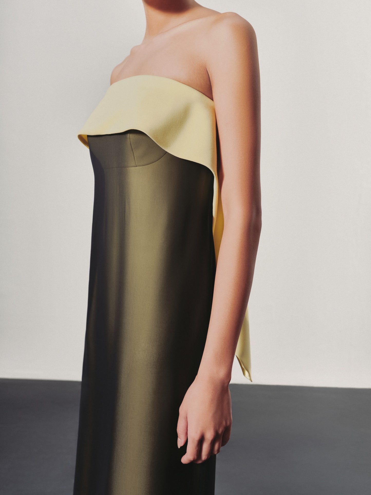 Woman wearing a strapless dress with a gradient from yellow to black on a plain background