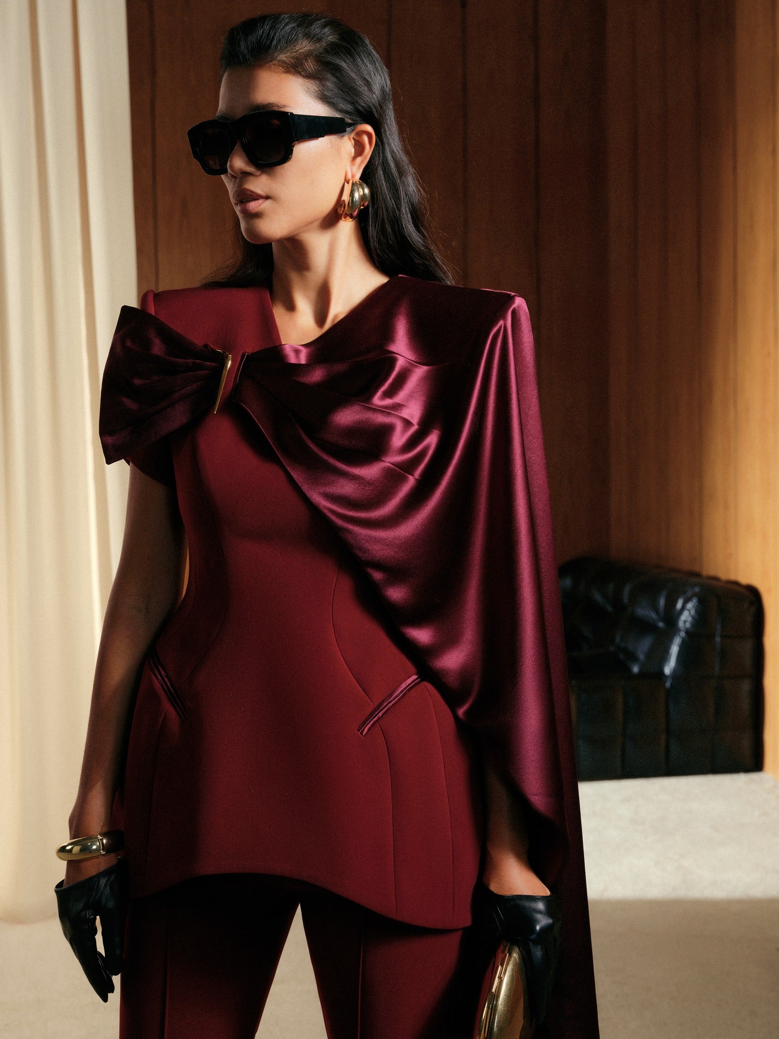 Woman wearing a burgundy outfit with a cape in an indoor setting
