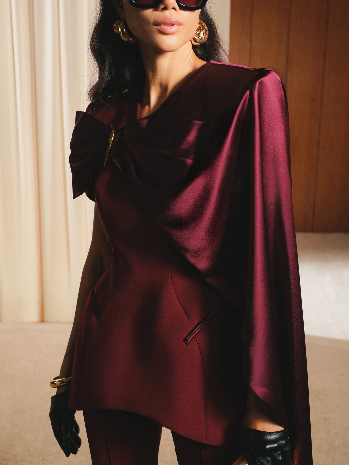 Person wearing a burgundy cape with a neutral background