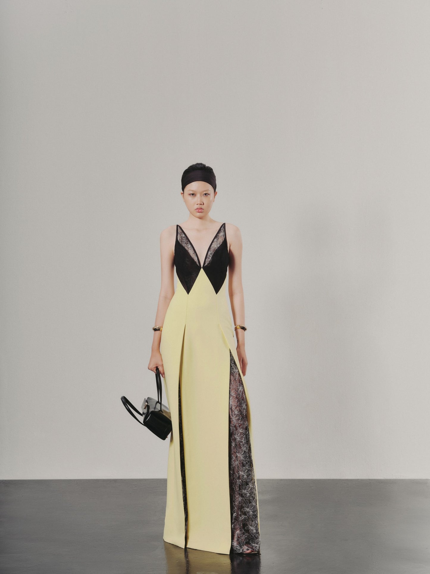 Woman wearing a yellow and black dress with sheer panels on a gray background