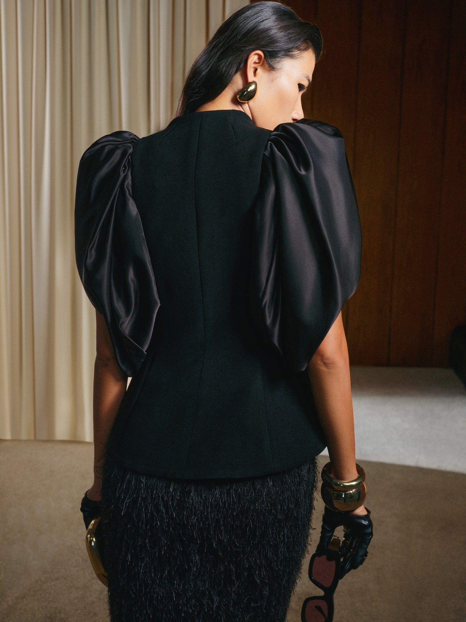 Woman wearing a black dress with puffed sleeves in an indoor setting