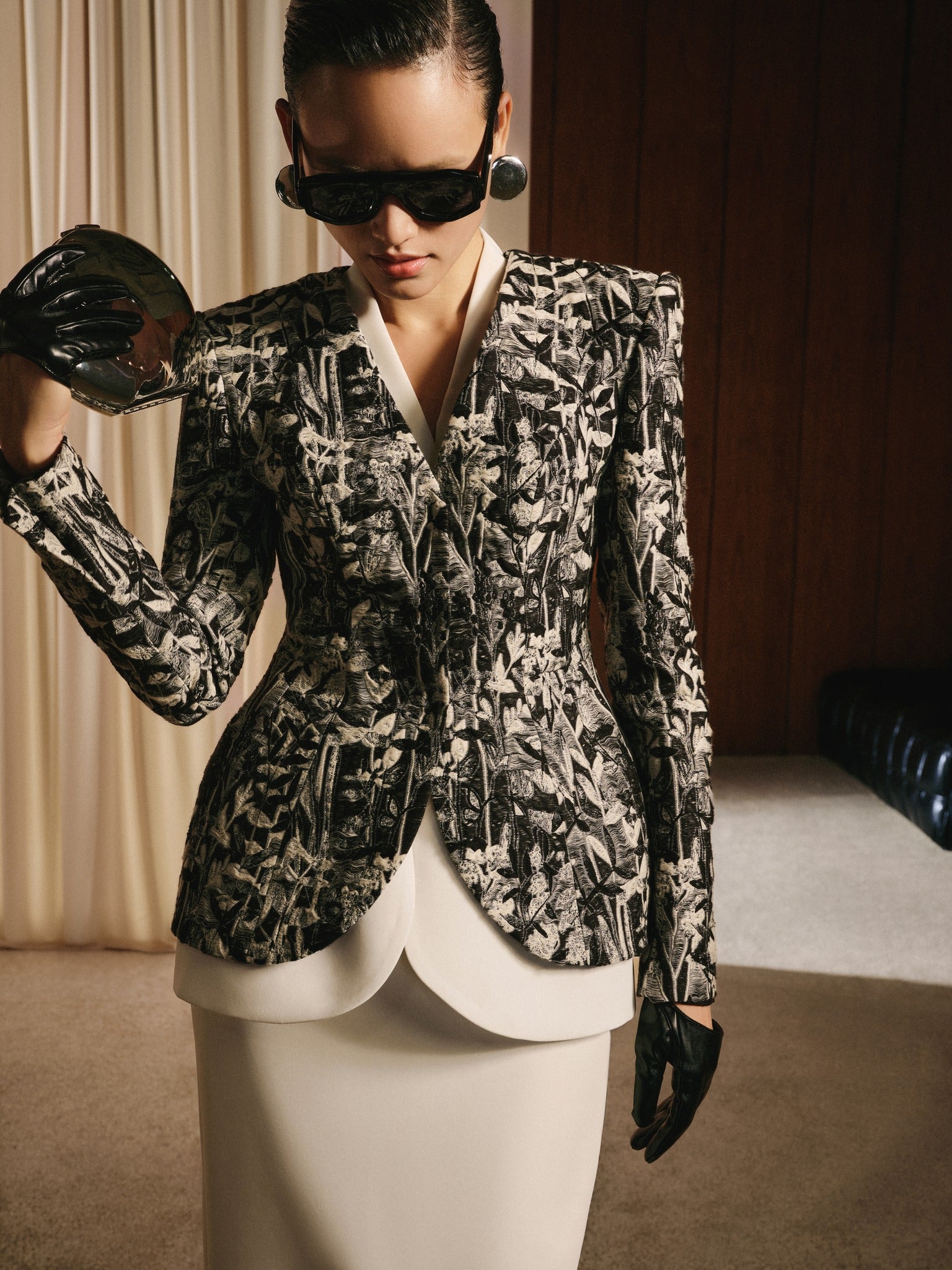 Woman wearing a patterned blazer and sunglasses indoors