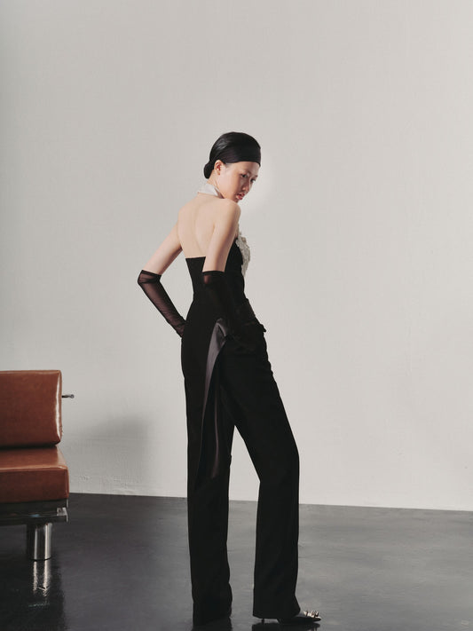 Woman in a black outfit standing against a plain background