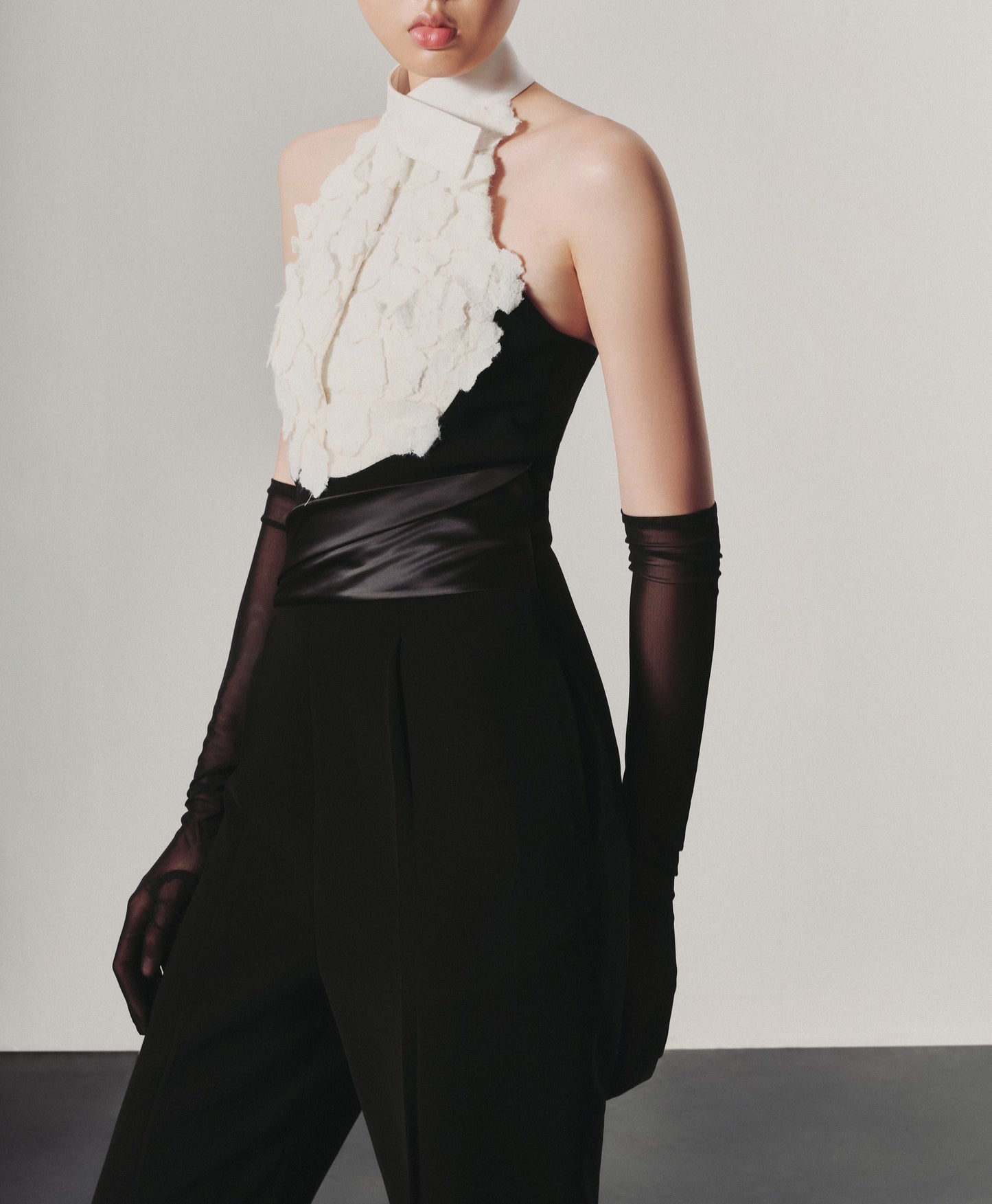 Person wearing a black and white outfit with a textured white top and high-waisted black pants.