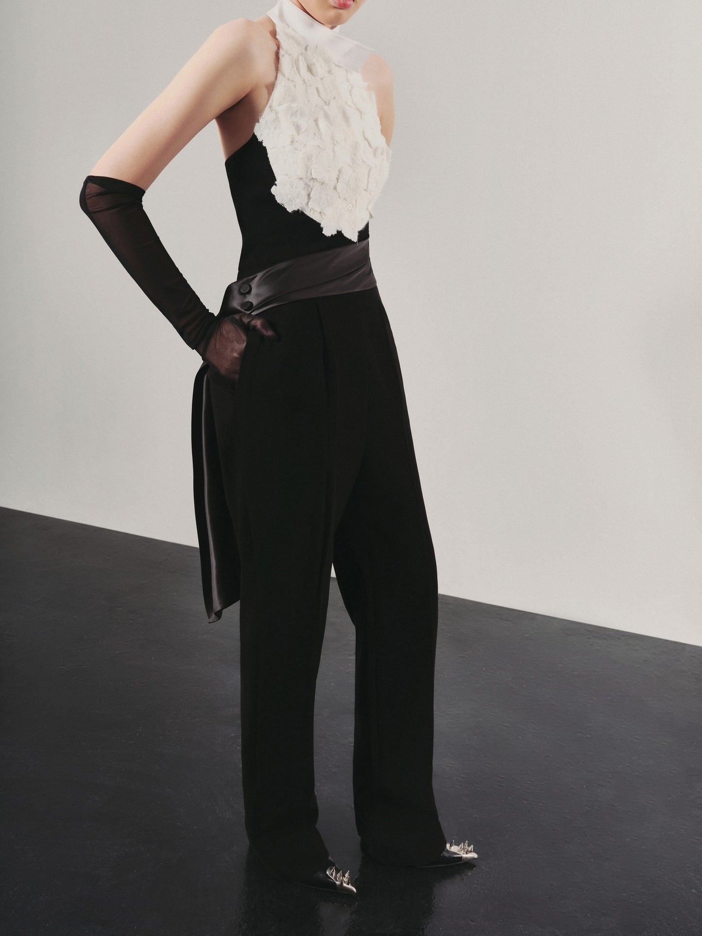 Person wearing a black outfit with a white floral top against a neutral background