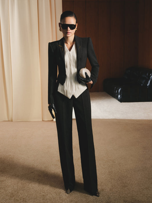 Person wearing a black suit and sunglasses in an indoor setting