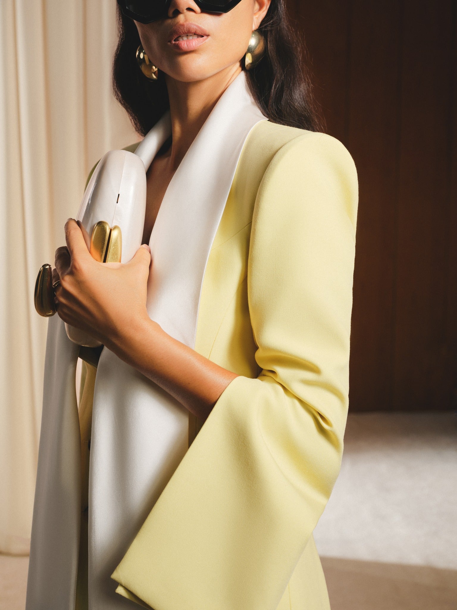 Woman in a yellow blazer and white top holding a gold object.