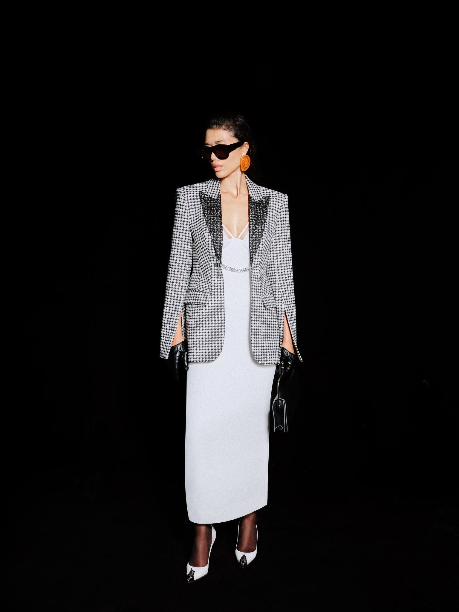 Woman wearing a checkered blazer and white dress on a black background