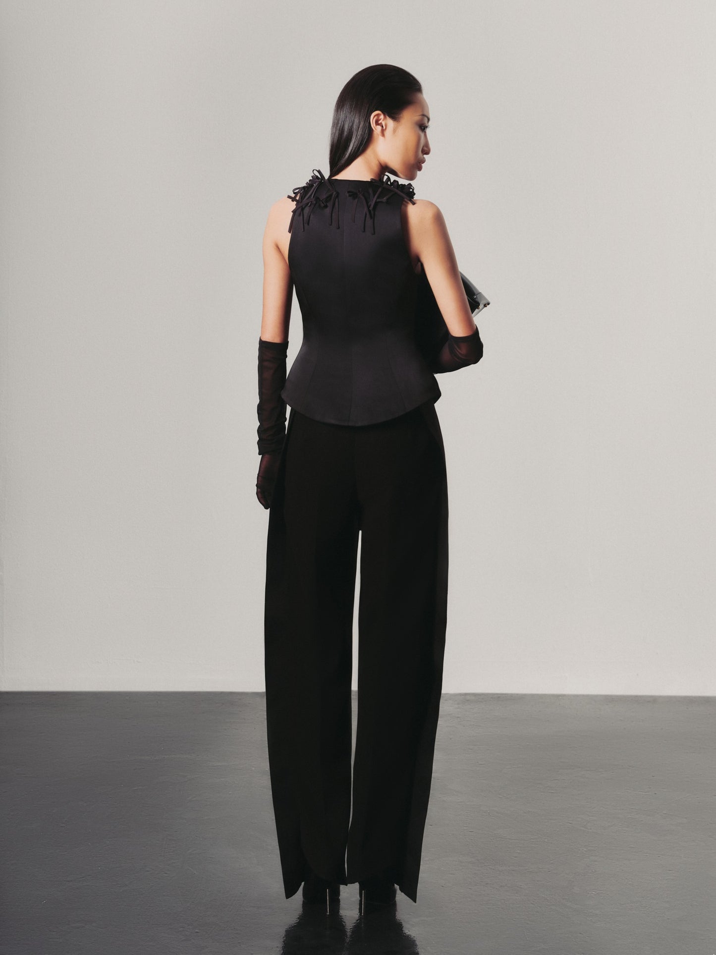 Woman wearing a black outfit with a high slit on a gray background