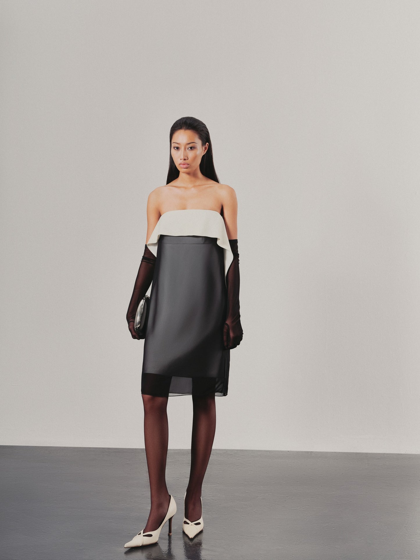 Model wearing a two-tone dress with a white top and black skirt on a plain background
