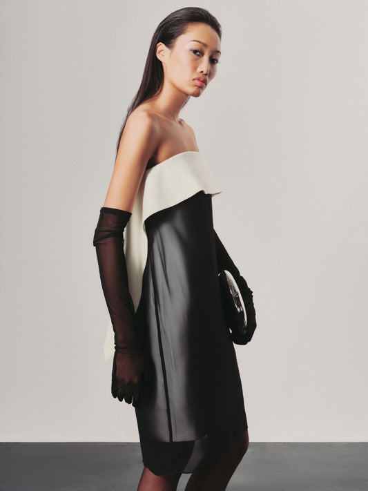 Woman wearing a two-tone dress with black and white colors on a plain background