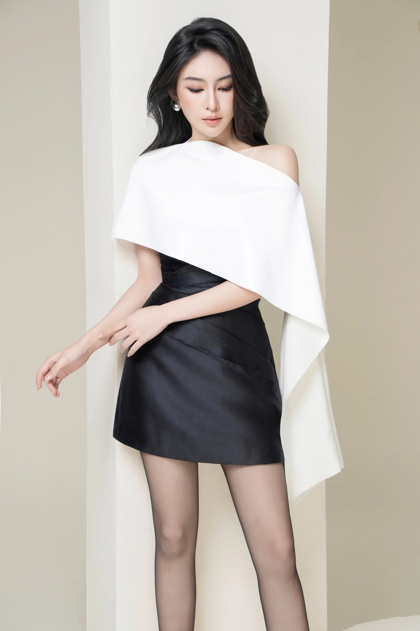 Woman wearing a black and white dress against a plain background