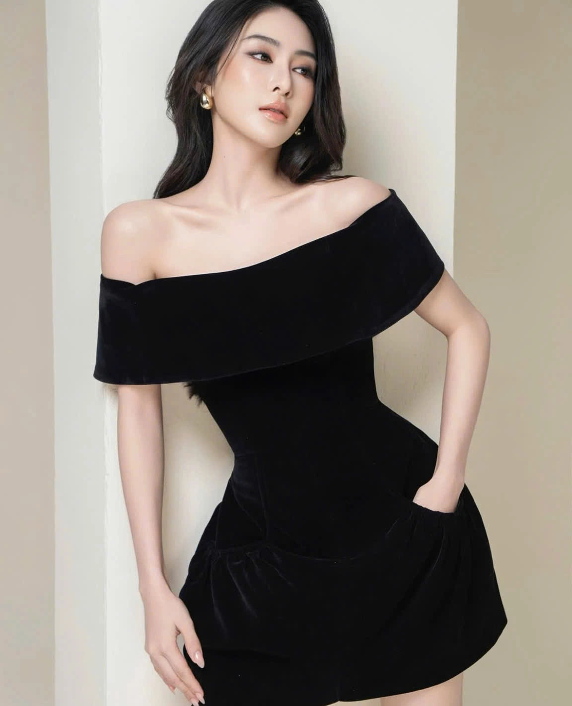 Woman wearing a black off-shoulder dress against a neutral background