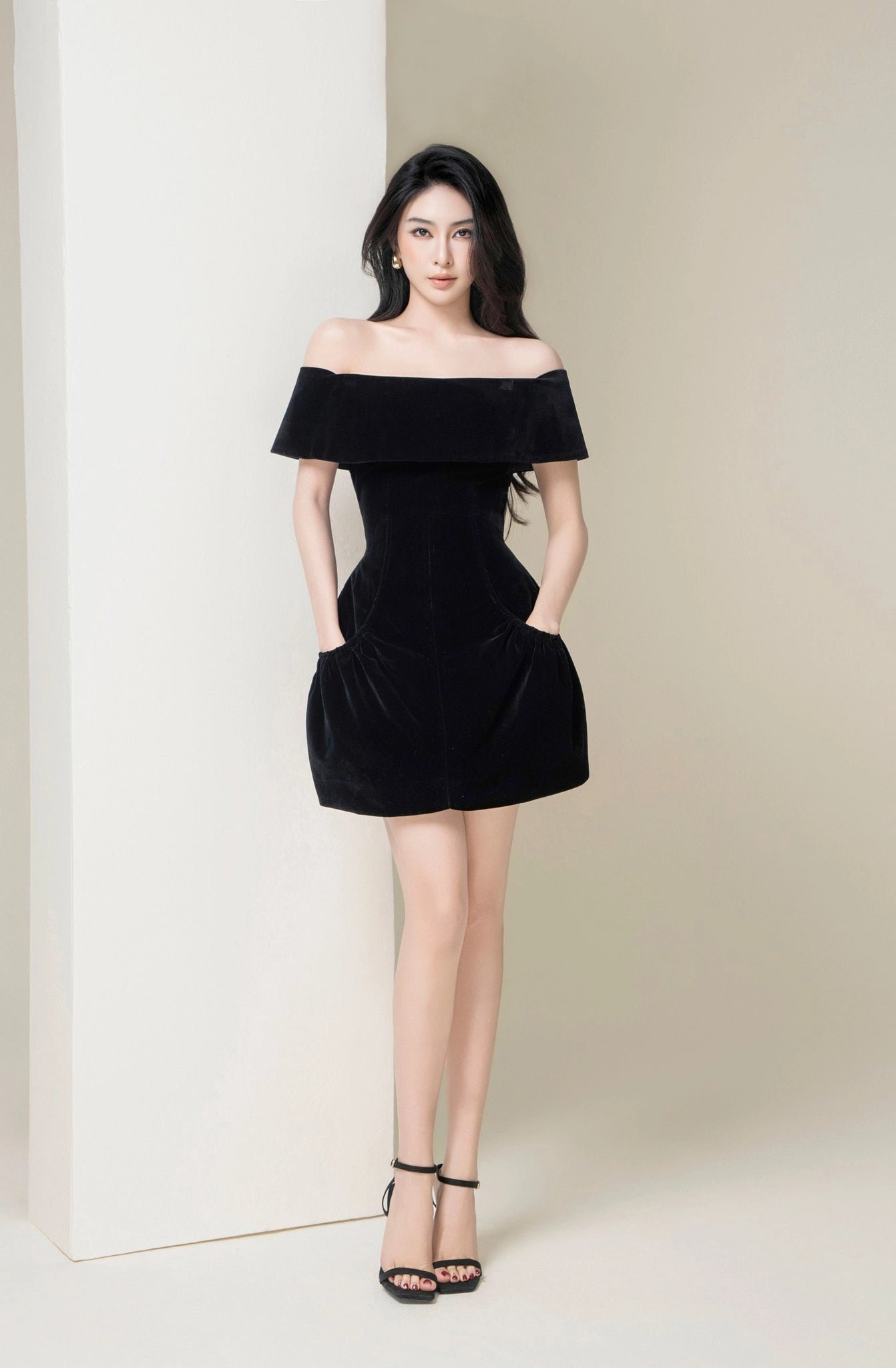 Woman wearing a black off-shoulder dress against a white background
