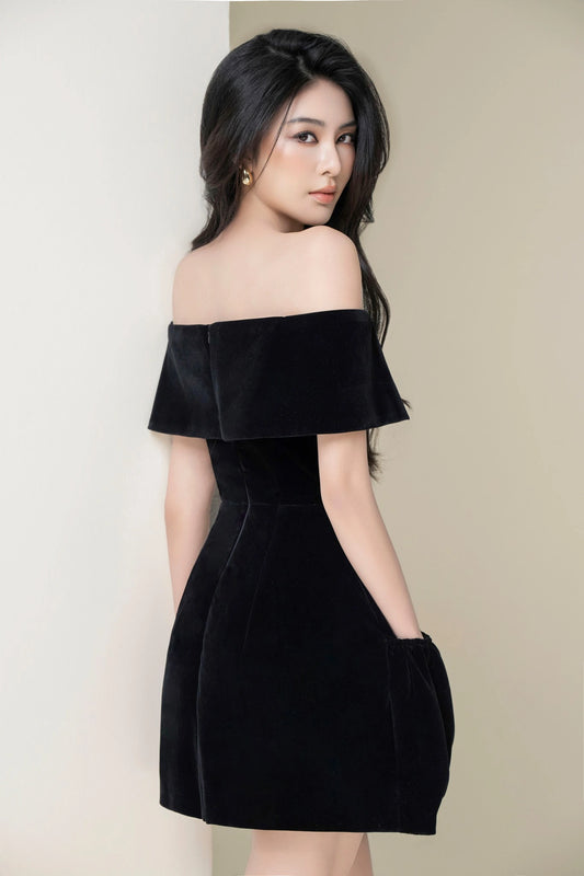 Woman wearing a black off-shoulder dress against a plain background