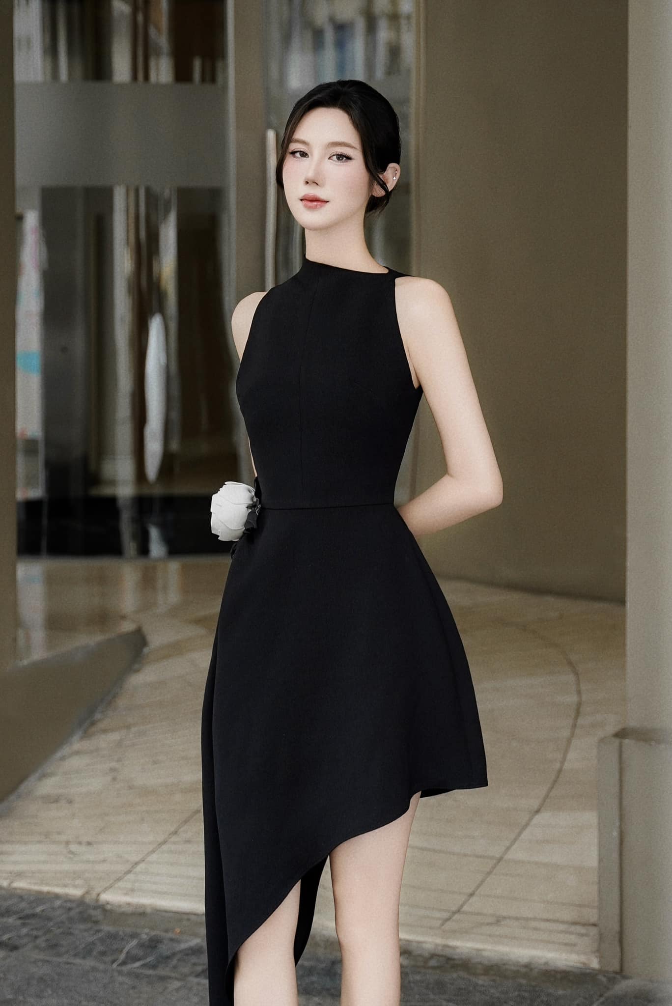 Woman in a black dress standing outdoors with a blurred background