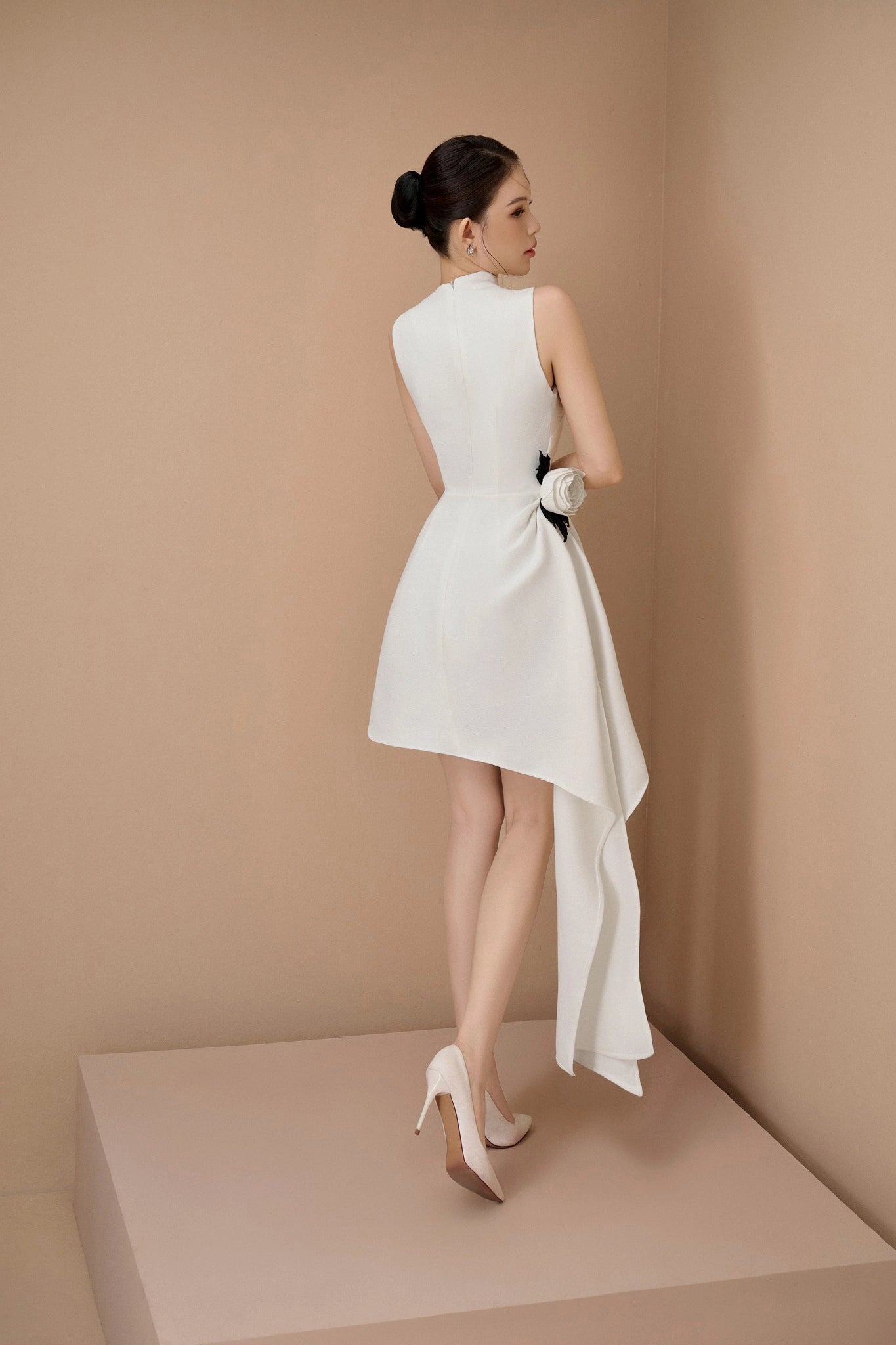 Woman wearing a white dress with a bow detail on a beige background