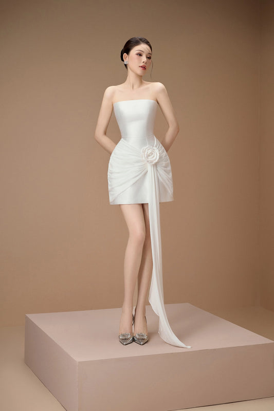 Woman wearing a white strapless dress with a long train on a beige background