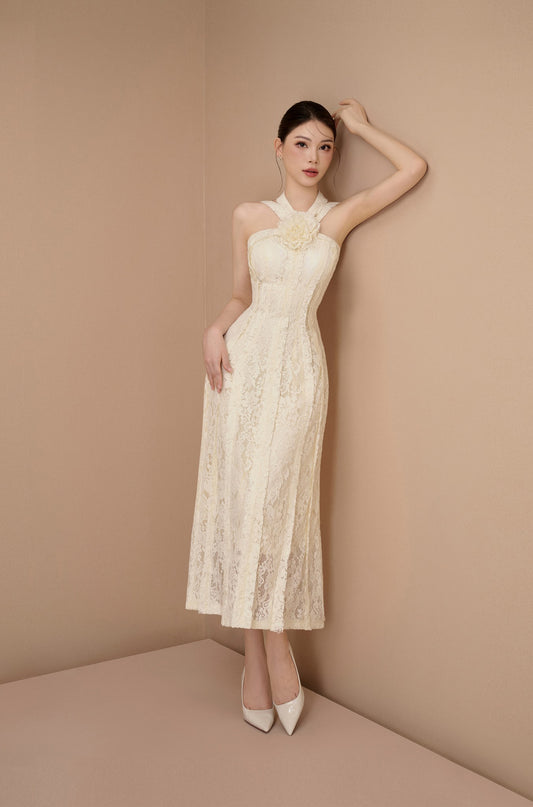 Woman in a white lace dress standing against a beige wall