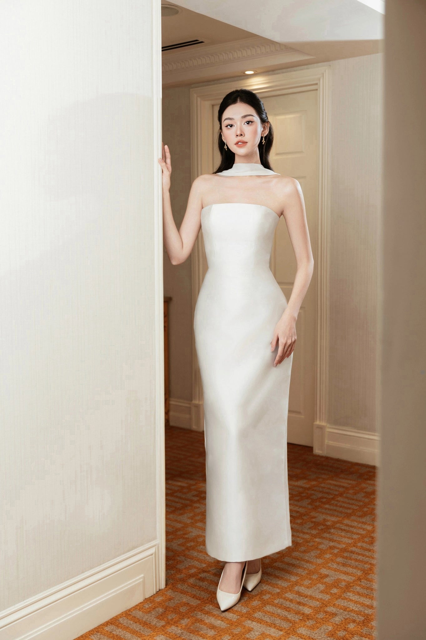 Woman in a white strapless gown standing in a doorway.