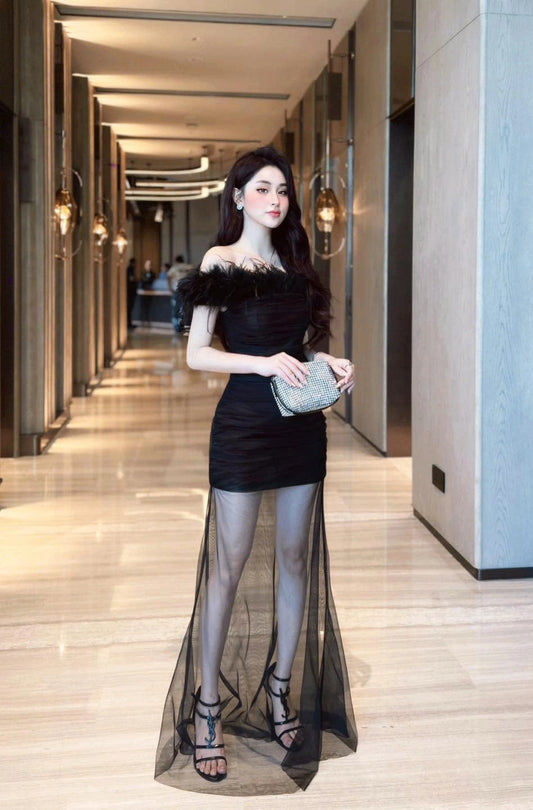 Woman in a black dress with sheer overlay in a hallway