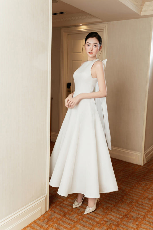 Woman in a white dress standing in an elegant interior setting