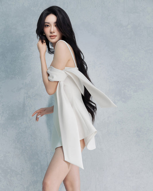 Woman wearing a white dress against a gray background