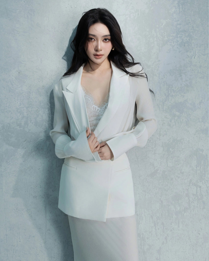 Woman wearing a light blue blazer and white top against a gray background
