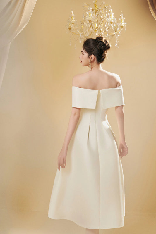 Woman wearing a white off-shoulder dress against a beige background