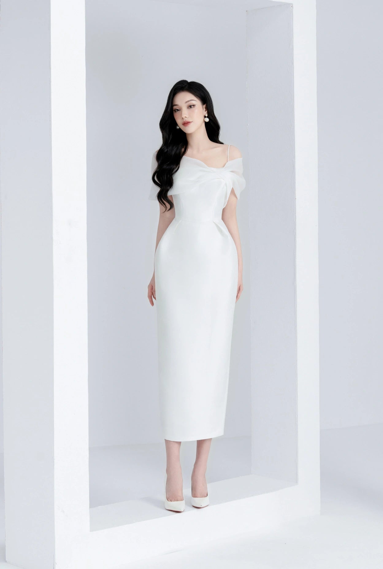 Woman in a white off-shoulder dress standing against a white background