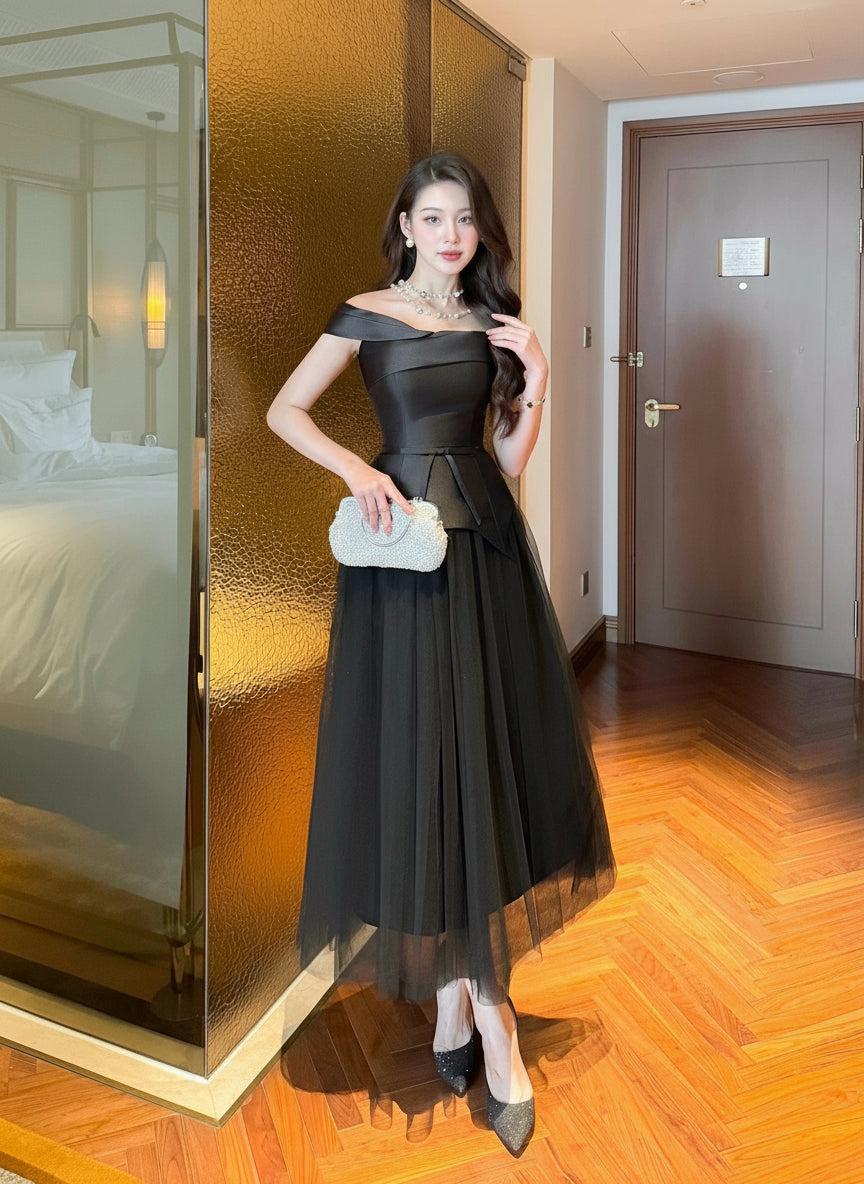 Woman in a black dress posing in a room with wooden flooring and a glass door.