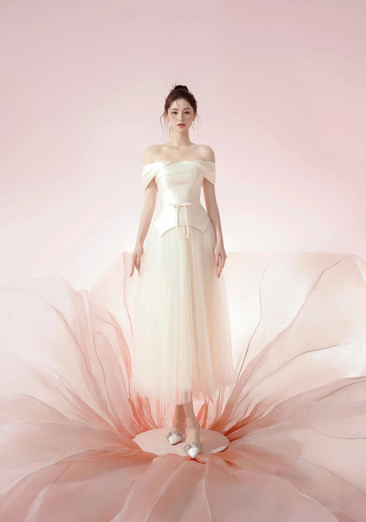 Woman wearing a light-colored off-shoulder dress with a soft pink background