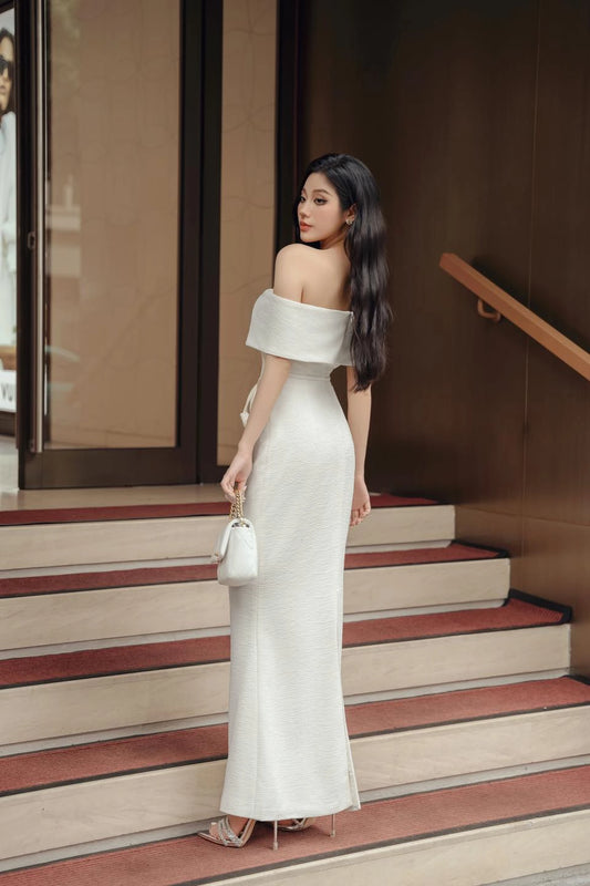 Woman in a white off-shoulder dress standing on steps